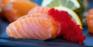 Slices of raw salmon with red fish roe and a slice of lemon
