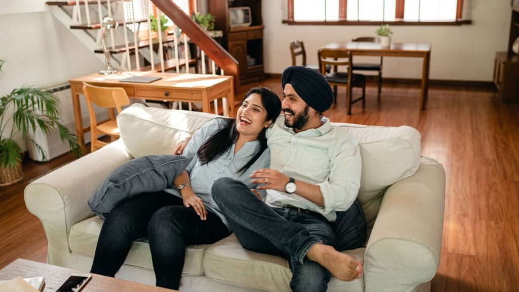 A couple laughing together on a sofa at home, with no visible signs of Chlamydia