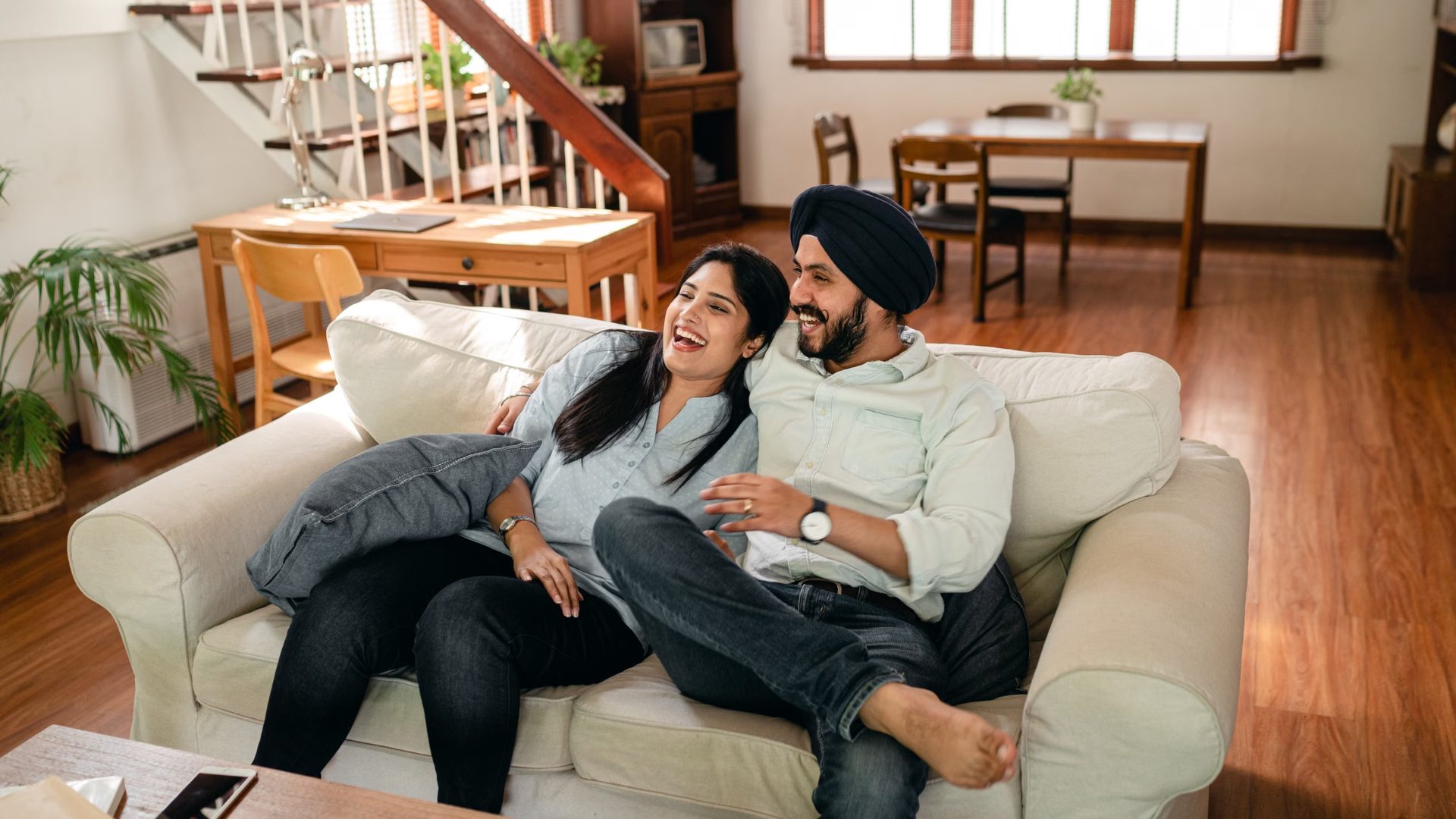 A couple laughing together on a sofa at home, with no visible signs of Chlamydia