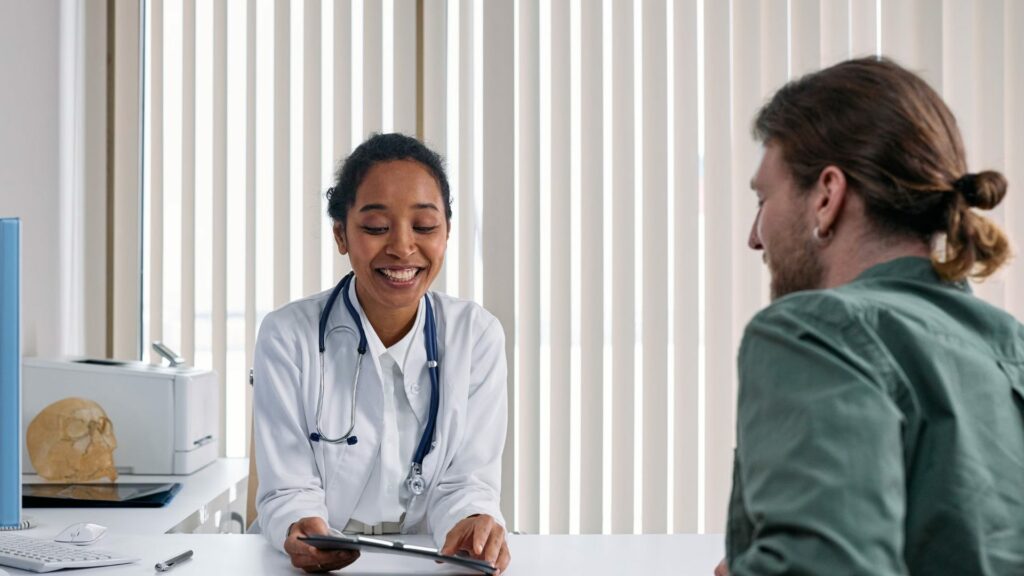 A smiling doctor talking with a male patient about Chlamydia testing at a private clinic