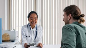 A smiling doctor talking with a male patient about Chlamydia testing at a private clinic