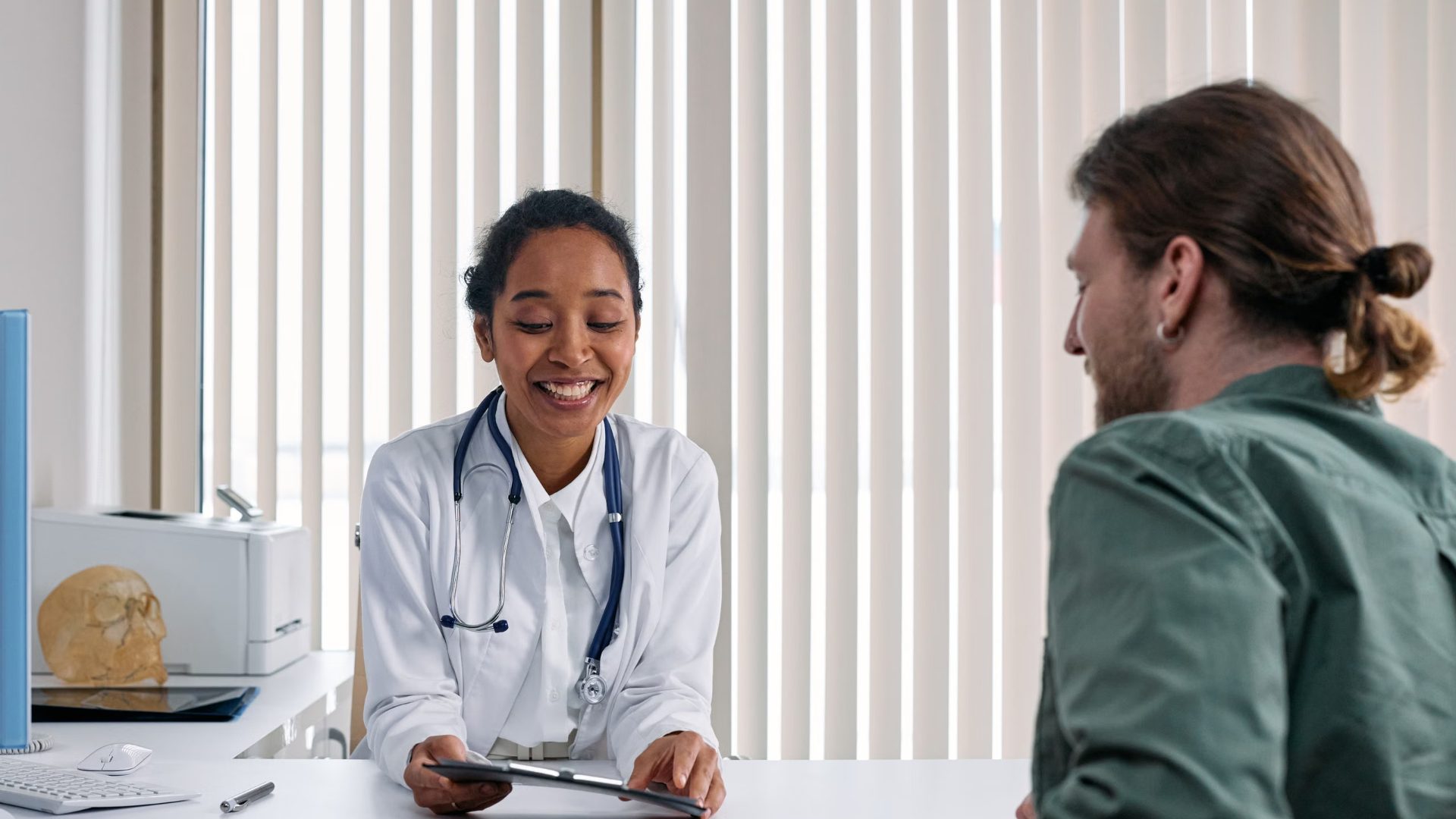 A smiling doctor talking with a male patient about Chlamydia testing at a private clinic