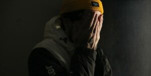 Un joven con gorro amarillo se tapa la cara con las manos