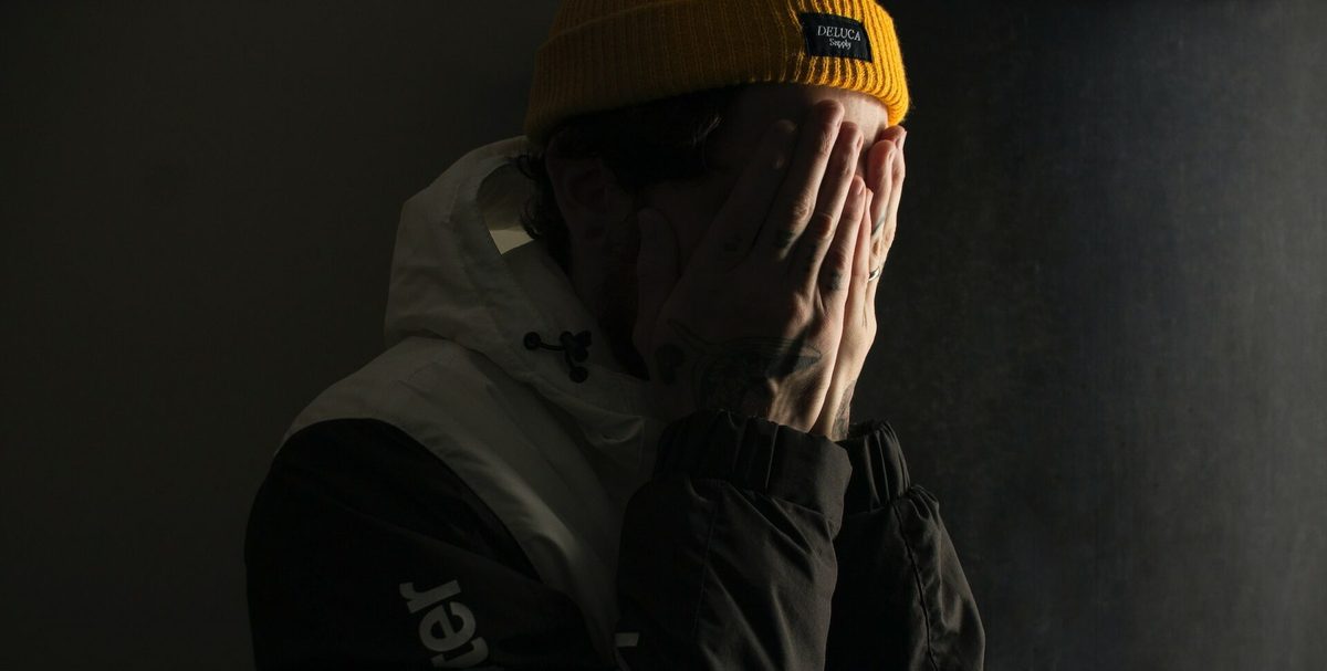 Un joven con gorro amarillo se tapa la cara con las manos
