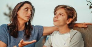 Una madre habla con su hijo adolescente sentados en un banco