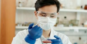 Investigador con guantes y mascarilla analizando una muestra en el laboratorio